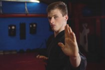 Young adult karate player performing karate stance in fitness studio — Stock Photo