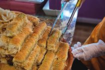 Крупный план продавщицы-женщины, занимающейся приготовлением турецких сладостей у прилавка в магазине — стоковое фото