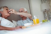 Seniorenpaar frühstückt auf Bett im Schlafzimmer — Stockfoto