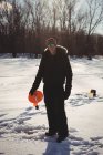 Pêcheur de glace adulte moyen tenant une bobine dans un paysage enneigé — Photo de stock