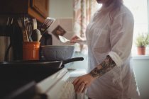 Sección media de la mujer de pie y preparando la comida en la cocina en casa - foto de stock