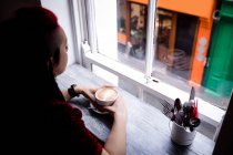 Mujer pensativa tomando café en la cafetería - foto de stock