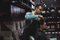 Barbeiro styling cabelo do cliente na barbearia — Fotografia de Stock