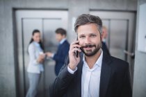 Hombre de negocios hablando por teléfono móvil en la oficina - foto de stock