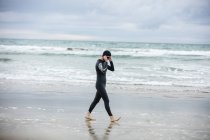 Atleta in muta che indossa occhiali da bagno mentre cammina sulla spiaggia — Foto stock