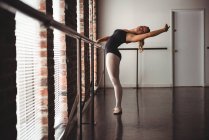 Bailarina practicando danza de ballet en bar en estudio de ballet - foto de stock