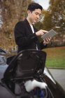 Homme utilisant une tablette numérique tout en rechargeant la voiture électrique à la station de charge du véhicule électrique — Photo de stock