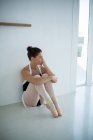 Nachdenkliche Ballerina sitzt im Ballettstudio auf dem Boden — Stockfoto
