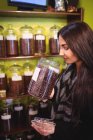 Hermosa mujer oliendo frasco de granos de café en la tienda - foto de stock