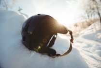 Capacete de esqui na paisagem nevada contra a luz solar brilhante — Fotografia de Stock