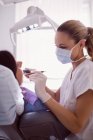 Dentista examinando paciente femenina en clínica - foto de stock