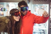 Пара в лижних окулярах приймає селфі за допомогою мобільного телефону — стокове фото