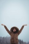 Donna sorridente in pelliccia godendo la nevicata durante l'inverno — Foto stock