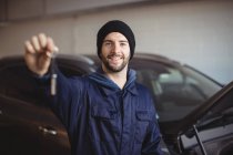 Portrait of mechanic in garage holding car key — Stock Photo