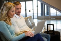 Couple sitting with laptop in the waiting area at airport terminal — Stock Photo