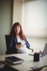 Femme d'affaires enceinte utilisant un téléphone portable au bureau — Photo de stock