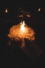 Manos recortadas de pareja sosteniendo bebidas quemando hoguera por la noche durante el invierno - foto de stock