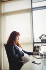 Schwangere Geschäftsfrau berührt Bauch, während sie Laptop im Büro benutzt — Stockfoto