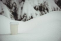 Одноразовая чашка кофе в снежном ландшафте зимой — стоковое фото