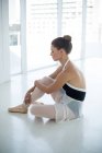 Печальная балерина сидит на полу в балетной студии — стоковое фото