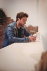 Чоловік використовує мобільний телефон за столом у кафе — стокове фото