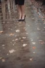 Ноги в стильной обуви бизнесвумен на мокрой пешеходной дорожке — стоковое фото