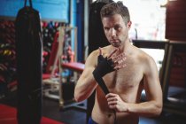Portrait of confident boxer wearing black strap on wrist in fitness studio — Stock Photo