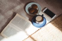 Книга, чай, печиво і мобільний телефон на підлозі вдома — стокове фото