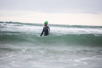 Atleta en traje de neopreno de pie en agua de mar - foto de stock