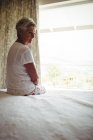 Беспокойная пожилая женщина сидит на кровати в спальне дома — стоковое фото