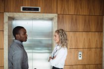 Бизнес-руководители, взаимодействующие с лифтом в офисе — стоковое фото