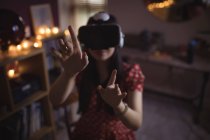 Frau gestikuliert mit Virtual-Reality-Headset zu Hause — Stockfoto