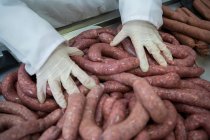 Close-up of butcher holding sausages at meat factory — Stock Photo