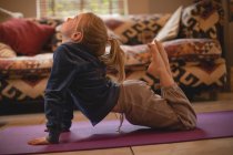 Chica realizando yoga en la sala de estar en casa - foto de stock