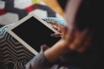 Sección media de la mujer que usa tableta digital en la sala de estar en casa - foto de stock