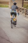 Rear view of athlete riding bicycle on road — Stock Photo