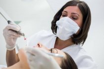 Zahnarzt untersucht Patientin mit Werkzeug in Zahnklinik — Stockfoto