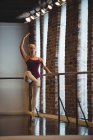 Ballerine pratiquant la danse de ballet à la barre en studio de ballet — Photo de stock
