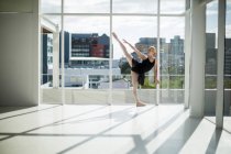 Ballerina stretching on a wall while practicing ballet dance in the studio — Stock Photo
