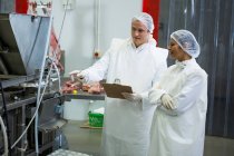 Techniker untersuchen Fleischverarbeitungsmaschine in Fleischfabrik — Stockfoto