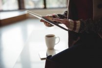 Mittelteil der Frau nutzt digitales Tablet beim Kaffee zu Hause — Stockfoto