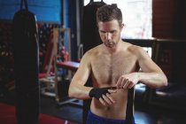 Confident boxer wearing black strap on wrist in fitness studio — Stock Photo