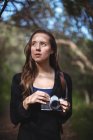 Schöne Frau steht mit Kamera im Wald — Stockfoto