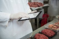 Mittlerer Abschnitt der Metzgerei führt Aufzeichnungen über digitales Tablet in Fleischfabrik — Stockfoto