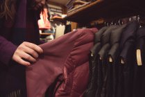Крупный план женщины, выбирающей одежду в магазине одежды — стоковое фото