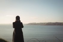 Вид ззаду жінки, що стоїть біля озера в парку протягом дня — стокове фото