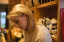 Mujer pensativa sentada en la cocina en casa - foto de stock