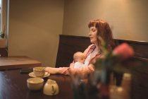 Madre con el bebé usando el teléfono móvil en la cafetería — Stock Photo