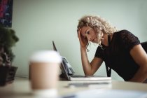 Donna d'affari frustrata che lavora su computer portatile in ufficio con caffè sulla scrivania — Foto stock