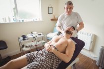 Fisioterapista che esamina il collo del paziente di sesso maschile in clinica — Foto stock